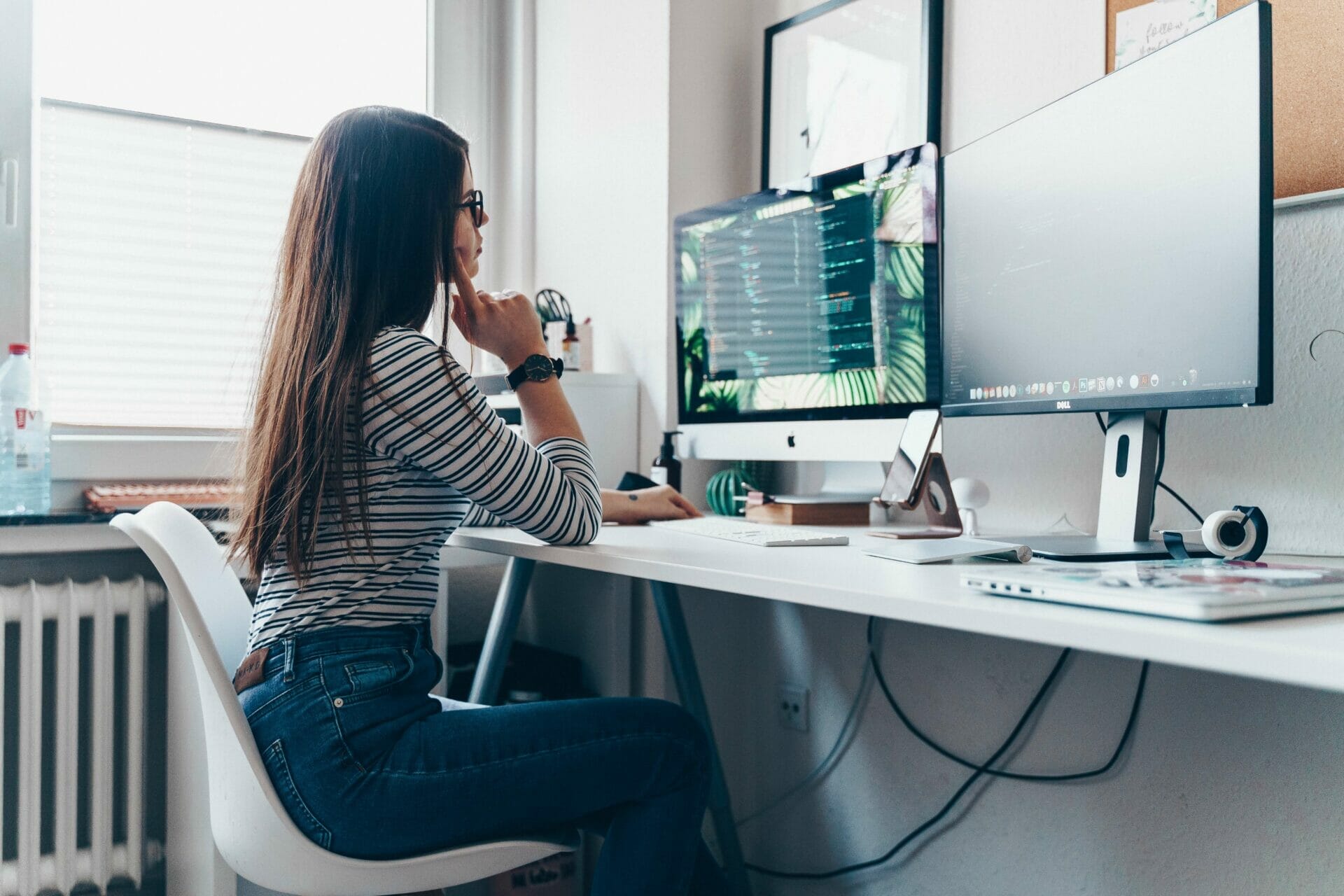 Young woman working with 2 monitors